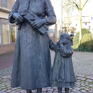 216-Aan het Sint Wilbertsplein staat “Ons moeder en het kind”, een beeld in brons, gemaakt in 1989 door Toon Grassens.